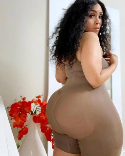 Woman in brown body suit, posing.